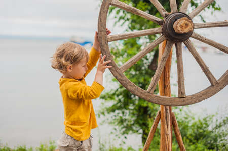 Cute child with wooden spinning-wheel outdoor against the seaの写真素材