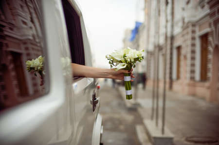 Bride's hand with a bouquet of lilies leaned out of the carの写真素材
