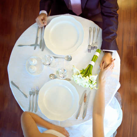 Served table for the bride and groom, Flat lay. Wedding. Decor. Serving. Artwork. Bride's and groom in a suit sitting at served tableの写真素材