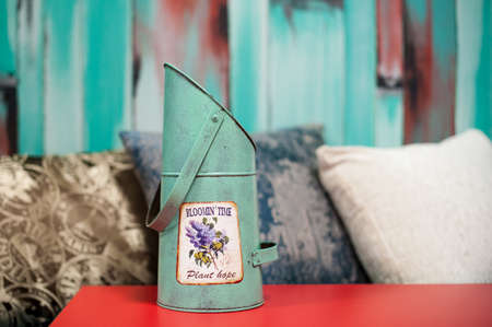 Turquoise flower bucket, against the backdrop of pillow and turquoise wooden wallの写真素材