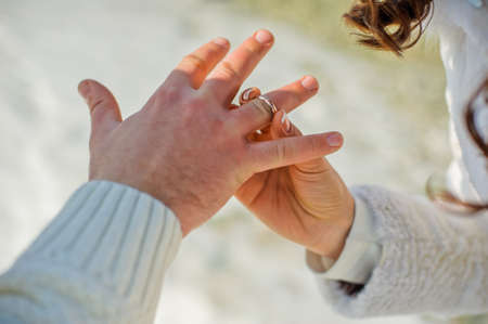 Groom wears bride a wedding ring on the background of snowの写真素材