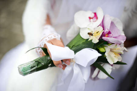 Bee on a bouquet of lilies at the hand of the brideの写真素材