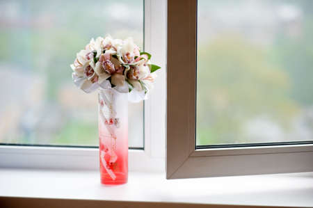 Red White bouquet of orchids on the windowの写真素材