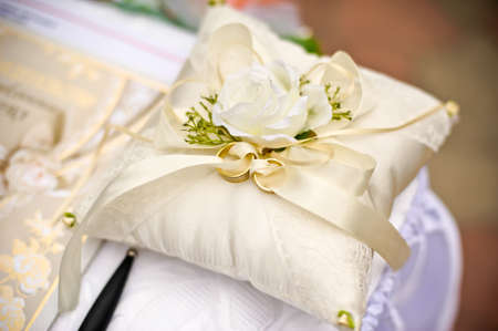 Gold wedding rings on a pillow with a flower ivoryの写真素材