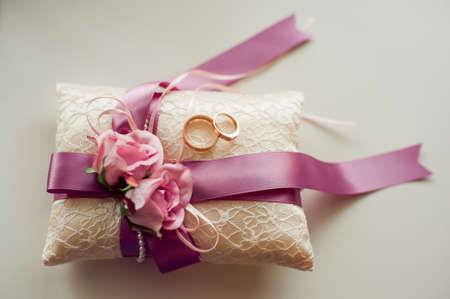 Golden wedding rings on decorated little pillow with purple ribbonsの写真素材