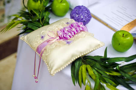 Golden wedding rings on decorated little pillow with purple ribbonsの写真素材
