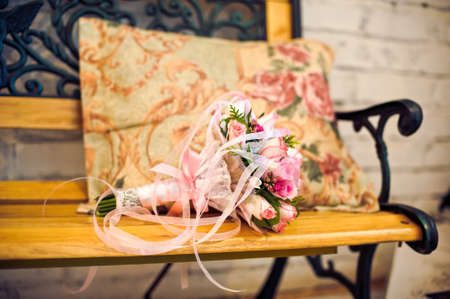 Pink wedding bouquet on a bench with a pillowの写真素材