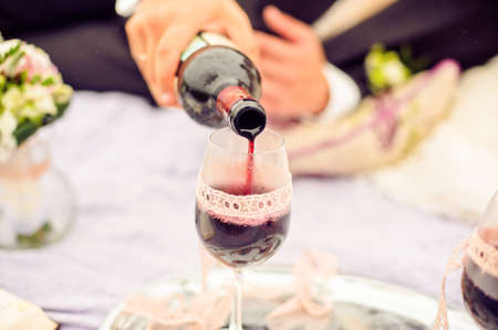 Groom wears bride a glass of red wineの写真素材