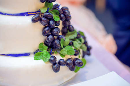White cake with grapes, leaves and blue ribbonsの写真素材
