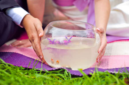 Bride and groom holding aquarium with goldfish Wedding conceptの写真素材