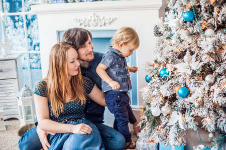 Family sitting by the fireplace and Christmas tree. Christmas conceptの写真素材