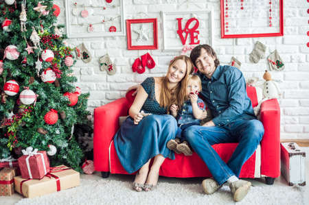Family in Christmas decorations on a red couch. Christmas conceptの写真素材