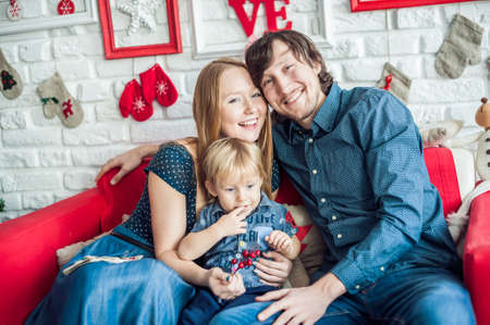 Family in Christmas decorations on a red couch. Christmas conceptの写真素材