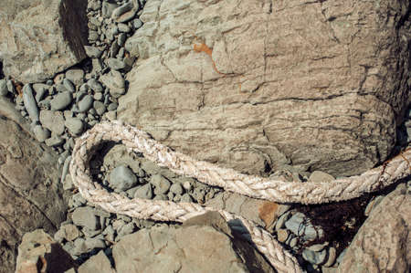 Old marine rope on a rocky seashoreの写真素材