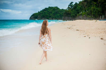 The girl walks on the water's edge on the island of Boracayの写真素材