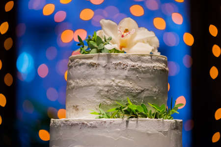 Split-level wedding cake with natural flowers on bokeh background with yellow lanternsの写真素材