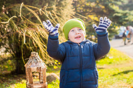 Happy little boy in winter clothes waving hands.の写真素材