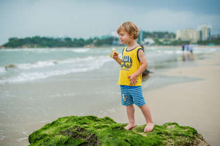 The boy cleans a banana on the seashoreの写真素材