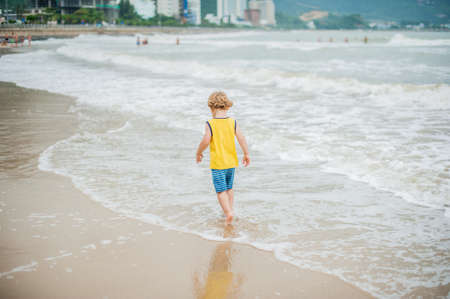 Baby boy walking on the sandy beach near the sea. Cute little kid at sand tropical beach. Ocean coast.の写真素材