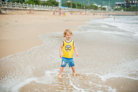 Baby boy walking on the sandy beach near the sea. Cute little kid at sand tropical beach. Ocean coast.の写真素材