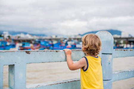 The boy looks at the blue bay with Vietnamese boatの写真素材