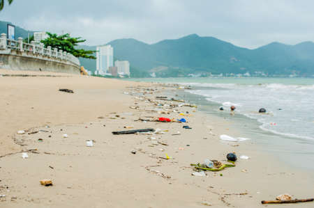 Beach pollution. Plastic bottles and other trash on sea beach in the rainの写真素材