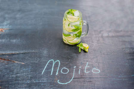 glass of mojito with lime and mint ice cube close-up on dark wood background. The inscription in chalk MOJITOの写真素材