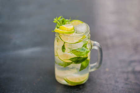 glass of mojito with lime and mint ice cube close-up on dark wood background.の写真素材