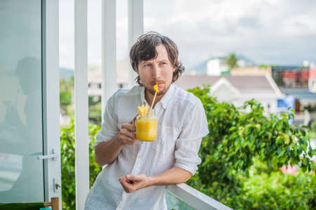 Pineapple cocktail with a slice of pineapple in the hands of a man on the terrace. Tropical cocktail concept.の写真素材