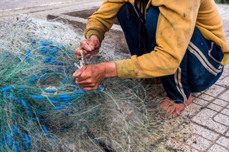 Hands of the old fisherman untangles fishing nets, Nha Trang, Vietnamの写真素材