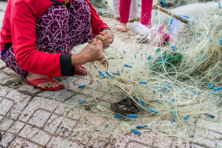 Hands of the old fisherman untangles fishing nets, Nha Trang, Vietnamの写真素材