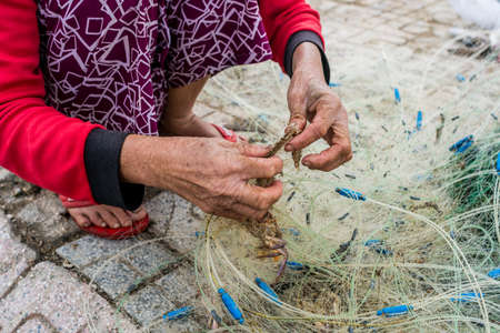 Hands of the old fisherman untangles fishing nets, Nha Trang, Vietnamの写真素材