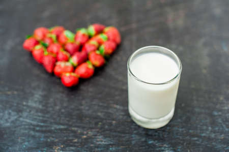 Fresh strawberries array heart shape and a glass of milk on old wooden background. Love concept. Valentine's Day Conceptの写真素材