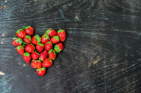 Fresh strawberries array heart shape on old wooden background. Love concept. Valentine's Day Conceptの写真素材