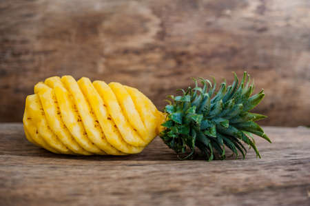 Pineapple slices and pineapple shelled Asian-style on the old wooden background. Tropical fruit concept.の写真素材
