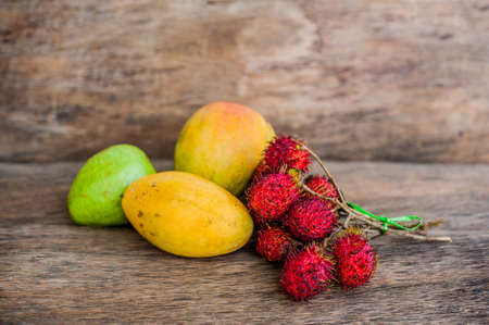 Tropical fruit on the old wooden background. Rambutan, banana, mango, guava. Tropical fruits conceptの写真素材