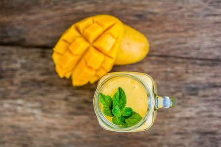 Mango smoothie in a glass Mason jar and mango on the old wooden background. Mango shake. Tropical fruit concept.の写真素材