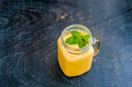 Mango smoothie in a glass Mason jar and mango on the old wooden background. Mango shake. Tropical fruit concept.の写真素材