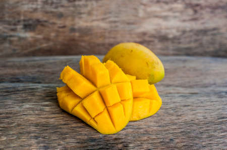 Mango fruit and mango cubes on the wooden table. Tropical fruit concept.の写真素材