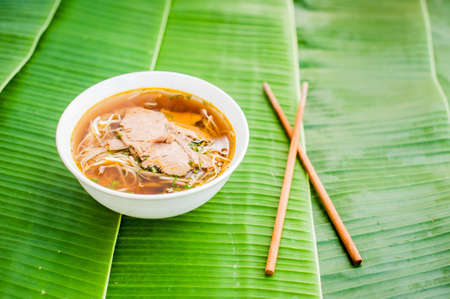 A bowl of Traditional Vietnamese beef soup Pho Bo on banana leaf background. ethnic meal. Vietnamese food conceptの写真素材