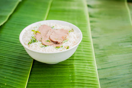 A bowl of Traditional Vietnamese beef soup Pho Bo on banana leaf background. ethnic meal. Vietnamese food conceptの写真素材