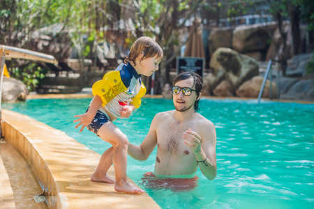 Young cheerful father and todler son in a swimming pool. Holidays with family concept.の写真素材