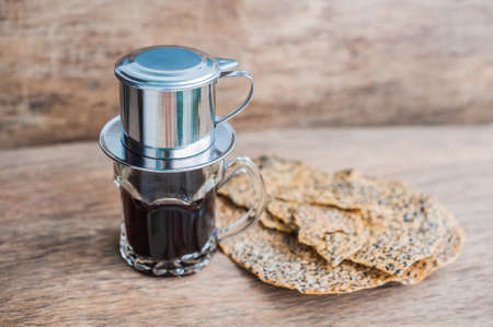 'Phin' traditional Vietnamese coffee maker, place on the top of glass, add ground coffee then pour hot water and wait until the coffee dripping into the glass. The Vietnamese Sesame Rice Cracker is called Banh Da and is made of tapioca flour, rice flour, の写真素材