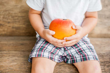 organic mango in hands on the old wooden background. tropical fruits conceptの写真素材