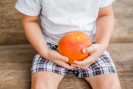 organic mango in hands on the old wooden background. tropical fruits conceptの写真素材