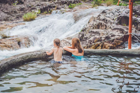 Geothermal spa. Mother and son relaxing in hot spring pool against the background of a waterfall. hot springs conceptの写真素材