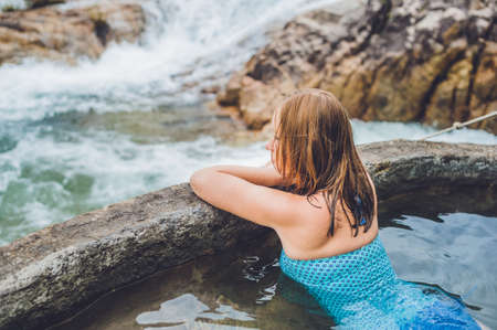 Geothermal spa. Woman relaxing in hot spring pool against the background of a waterfall. hot springs conceptの写真素材