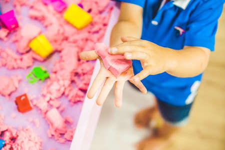 Boy playing with kinetic sand in preschool. The development of fine motor concept. Creativity Game...