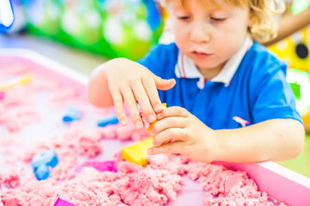 Boy playing with kinetic sand in preschool. The development of fine motor concept. Creativity Game concept.の写真素材