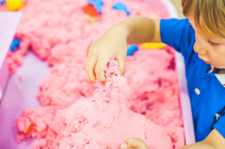 Boy playing with kinetic sand in preschool. The development of fine motor concept. Creativity Game concept.の写真素材